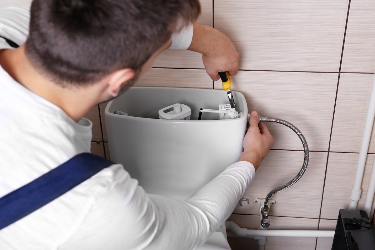 Plombier réparant la chasse d'eau des toilettes dans les toilettes.