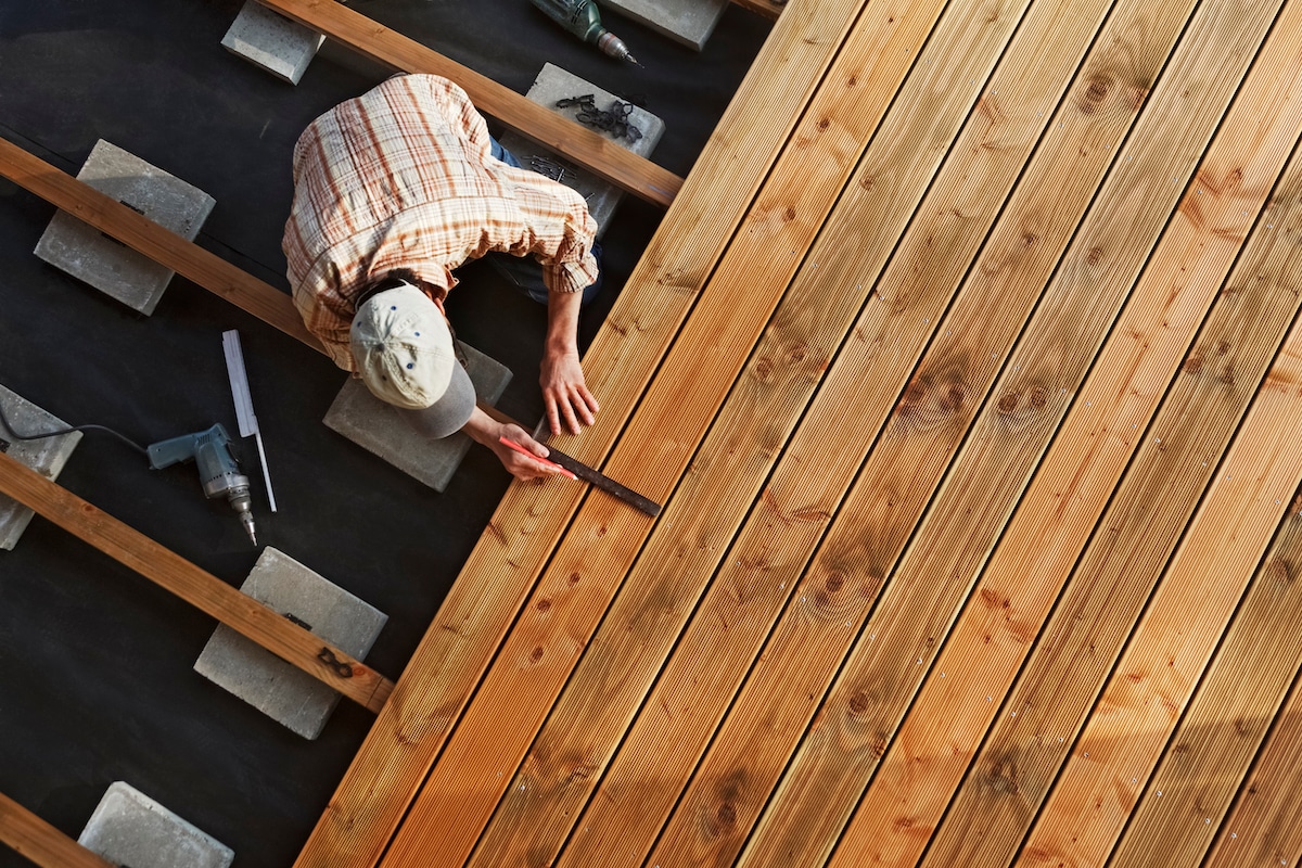 Un homme construit le plancher en bois d'une terrasse