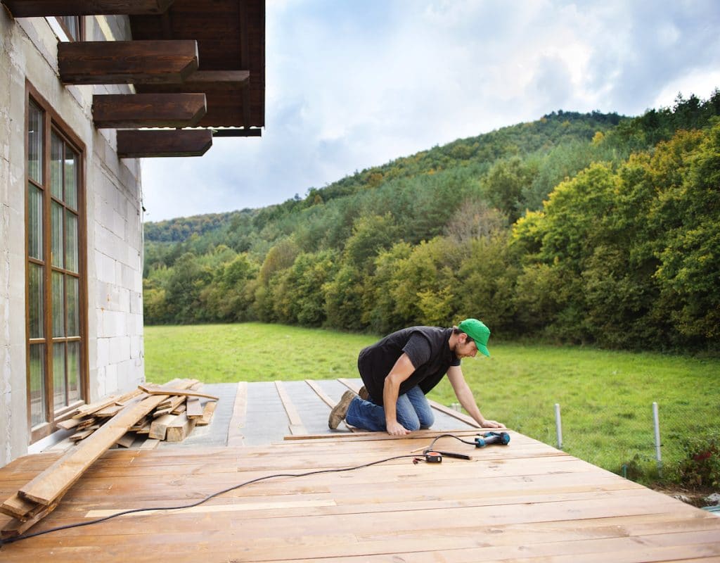 Un homme travaille à l'installation d'une terrasse en ipé en bord de forêt. 