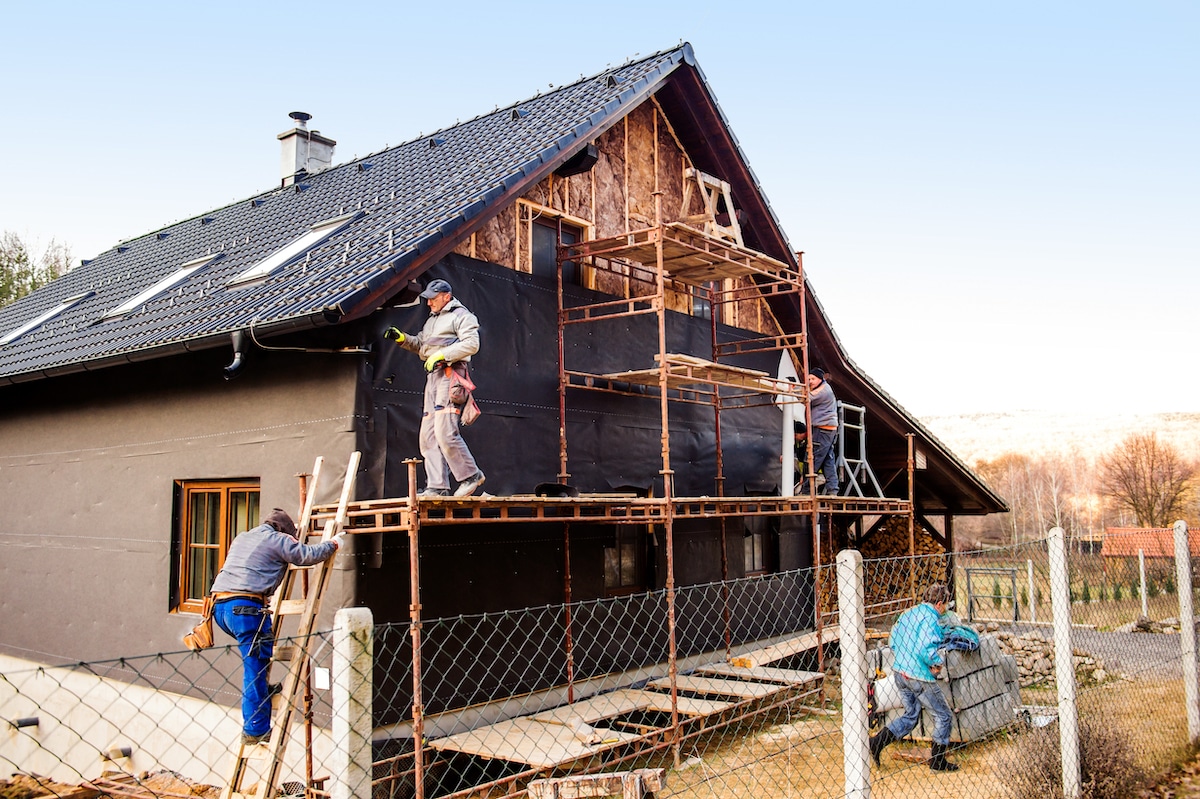 Ouvriers du bâtiment isolant thermiquement une maison en bois avec de la laine de verre