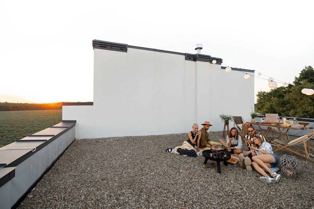 Un groupe d'amis se réchauffent autour du Braséro installé sur leur terrasse en gravier.