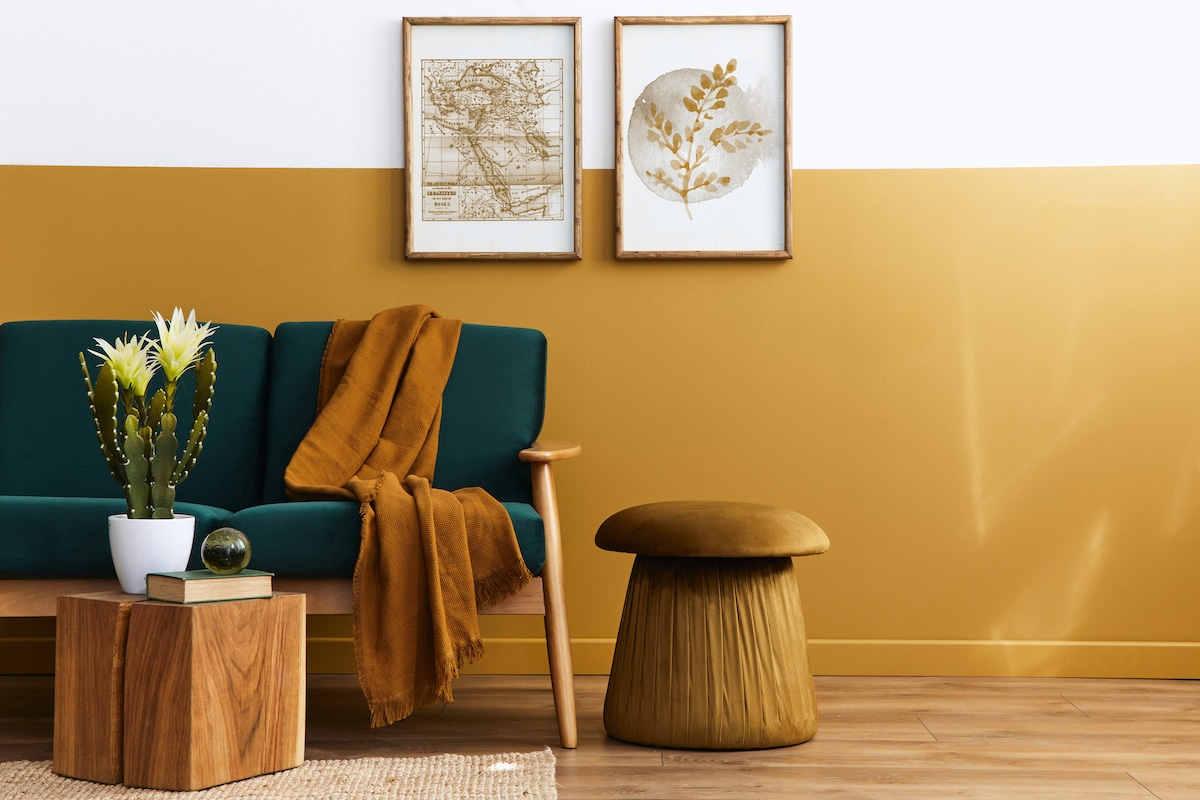 Intérieur scandinave élégant de salon avec canapé design en velours vert, pouf doré, meubles en bois, cactus, tapis, cube, espace de copie et cadres d'affiche mock up. Modèle.